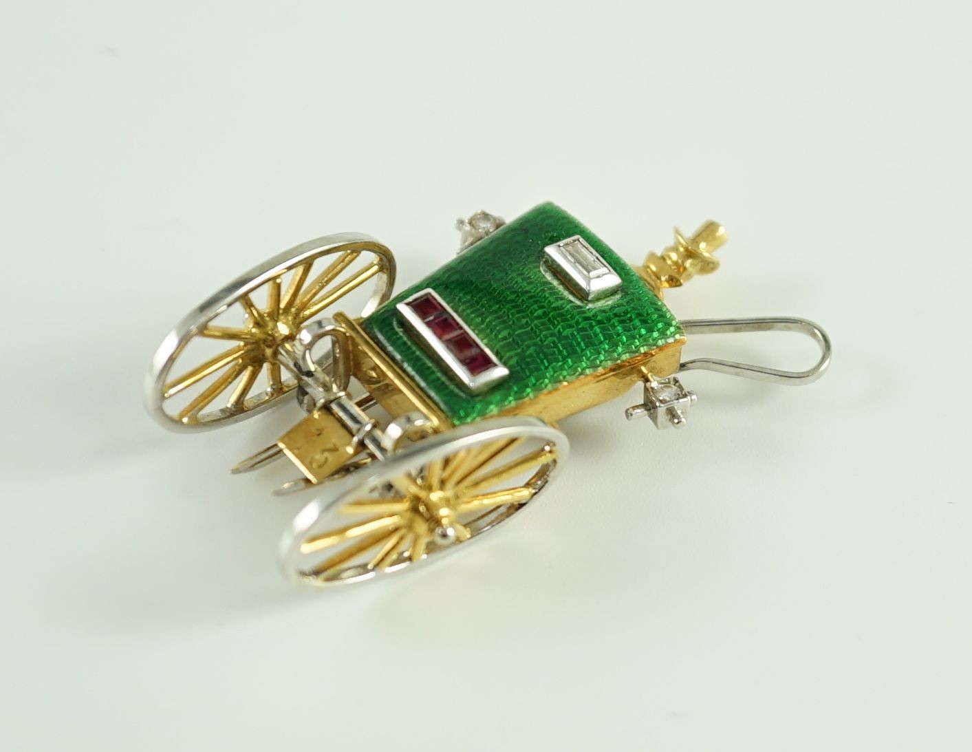A mid 20th century Italian two colour 18ct gold, green enamel, ruby and diamond set novelty clip brooch, modelled as the rear view of a carriage with driver